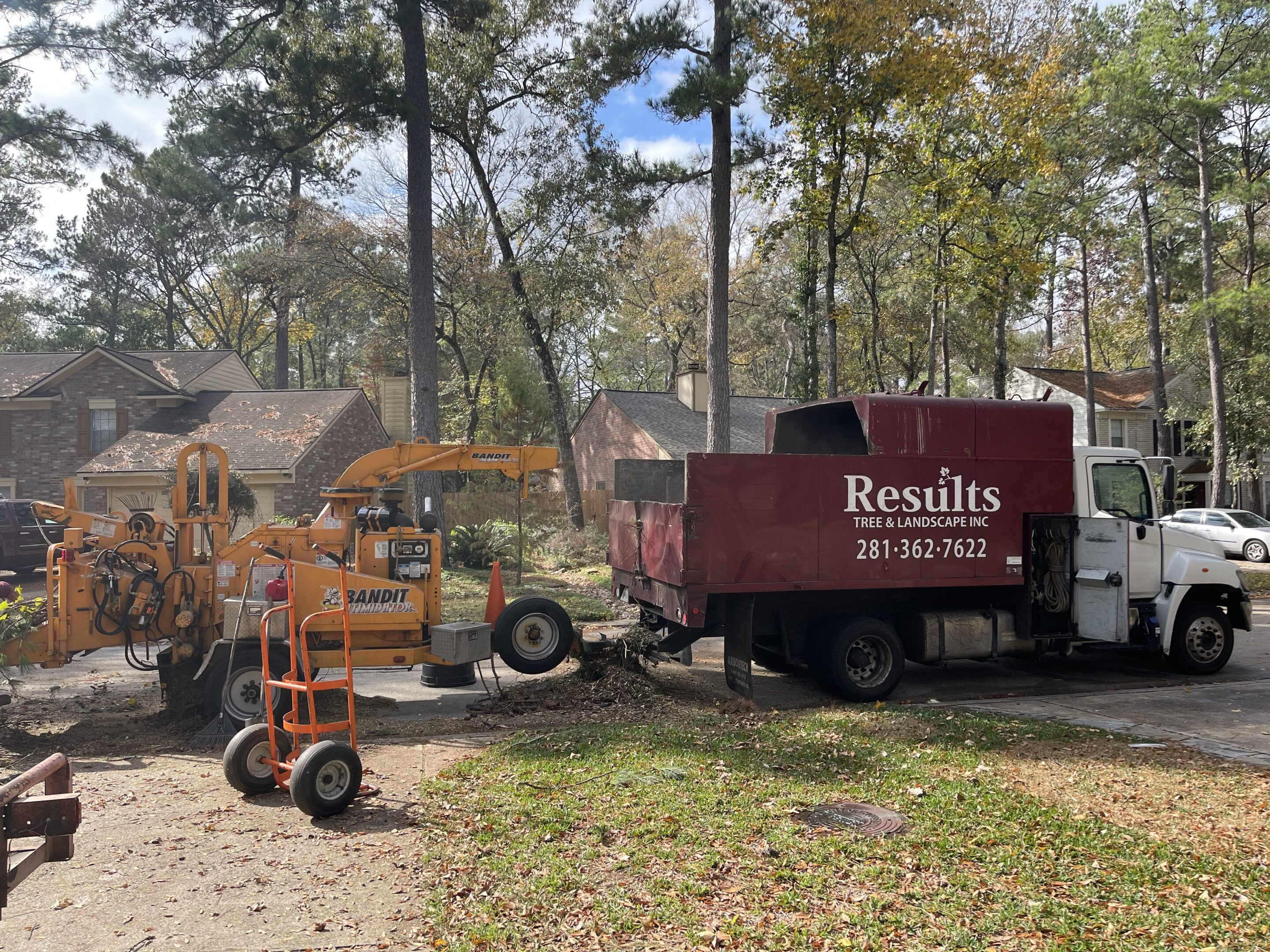 Results Tree & Landscape Inc. branded dump truck and heavy-duty wood chipper performing residential tree care and removal services in Magnolia, Texas.